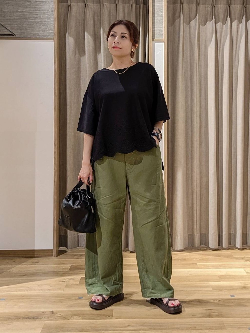 グリーン系のデニムパンツ、ブラック系のTシャツ/カットソー、ブラウン系のサンダルを着用したレディースの夏コーディネートの3枚目の写真