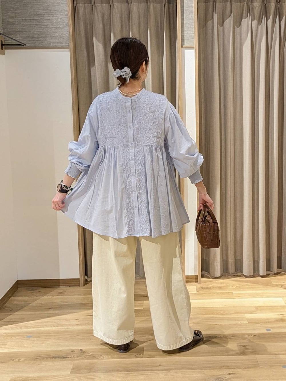 イエロー系のチノパンツ、ブラウン系のトートバッグ、ブルー系のシャツ/ブラウスを着用したレディースの冬コーディネートの2枚目の写真