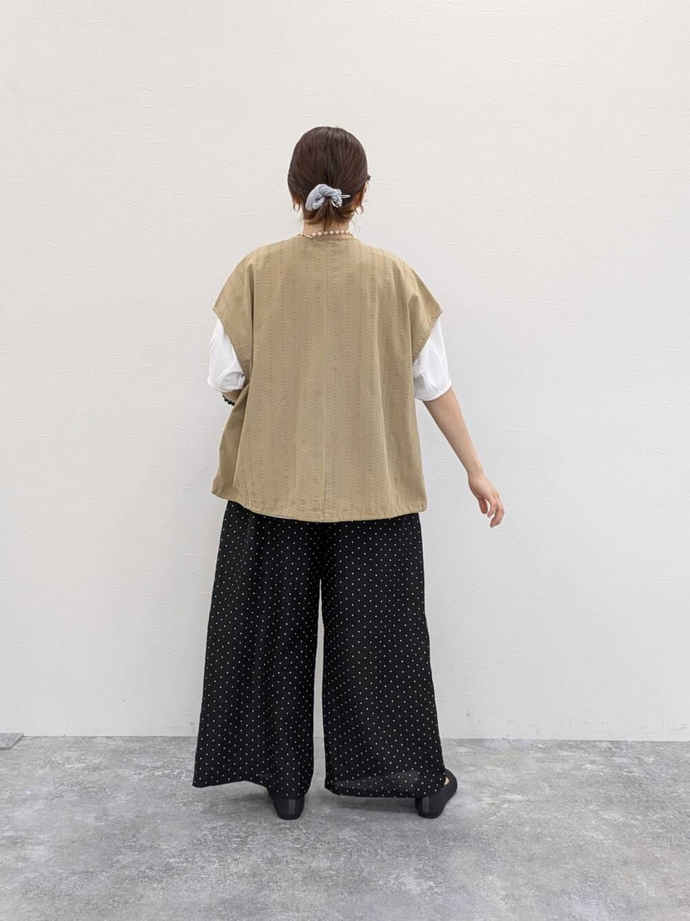 グレー系のパンプス、ベージュ系のベスト、ホワイト系のTシャツ/カットソーを着用したレディースの春コーディネートの2枚目の写真