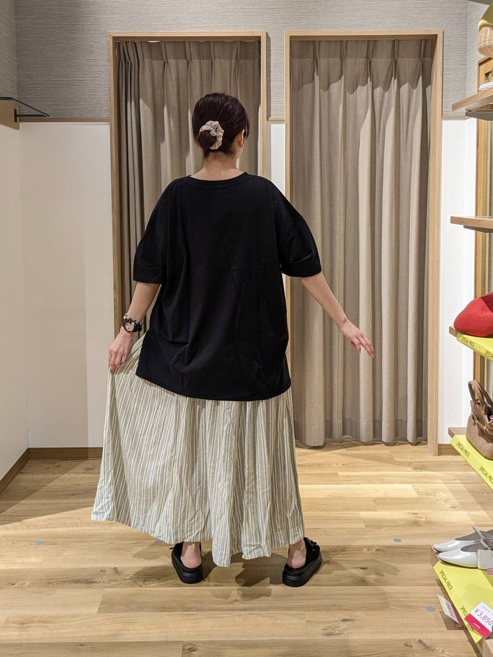 イエロー系のスカート、ブラウン系のショルダーバッグ、ブラック系のサンダルを着用したレディースの春コーディネートの2枚目の写真