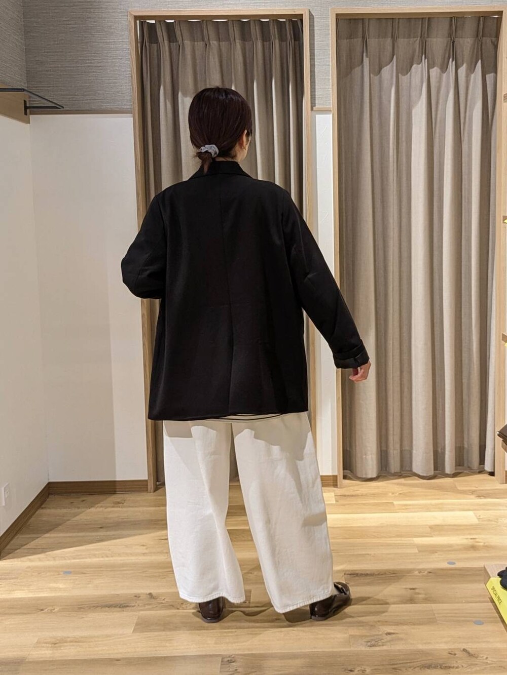 ブラック系のテーラードジャケット、ホワイト系のデニムパンツ、ベージュ系のトートバッグを着用したレディースの春コーディネートの2枚目の写真