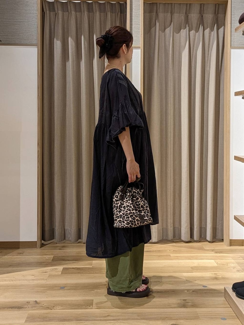 グリーン系のデニムパンツ、ブラウン系のサンダル、ブラック系のワンピースを着用したレディースの夏コーディネートの2枚目の写真