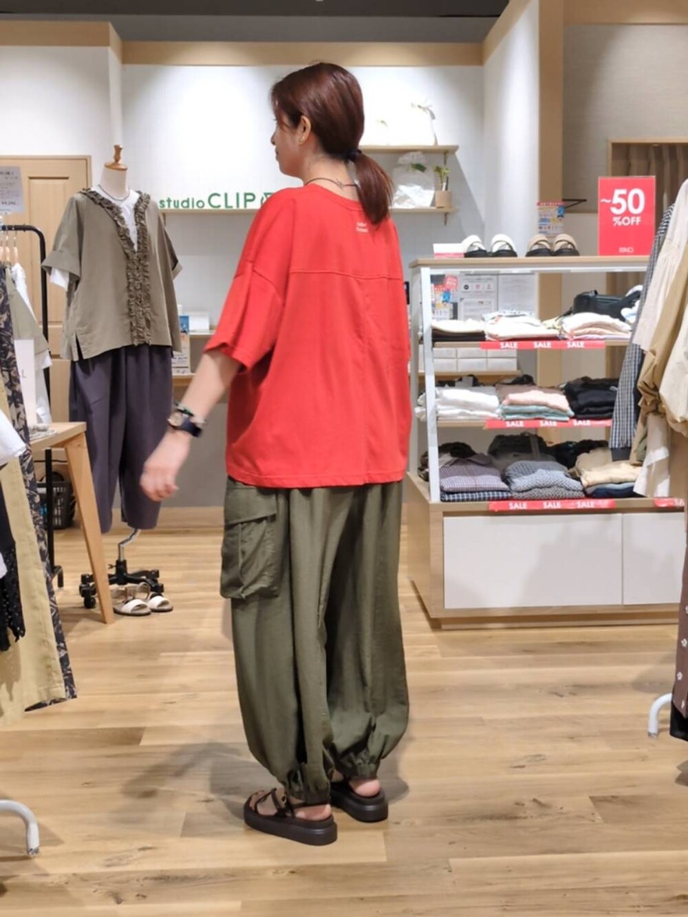グリーン系のカーゴパンツ、レッド系のTシャツ/カットソー、ブラウン系のサンダルを着用したレディースの夏コーディネートの2枚目の写真