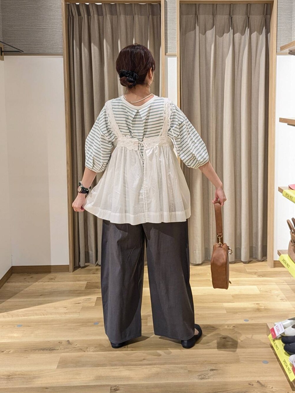 ホワイト系のベスト、ブラウン系のショルダーバッグ、グレー系のパンプスを着用したレディースの春コーディネートの2枚目の写真