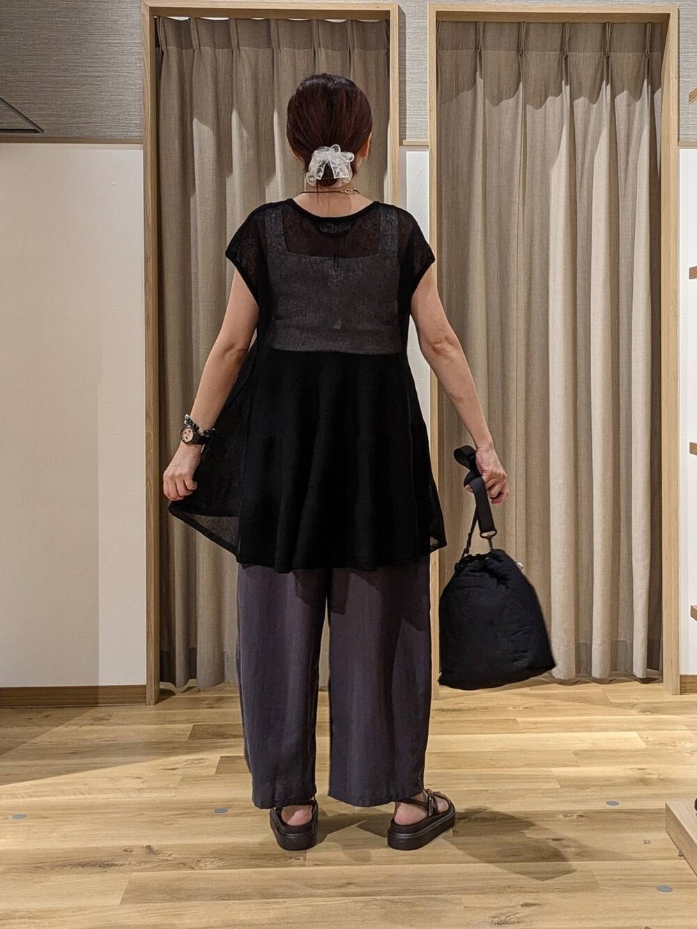 ブラック系のニット/セーター、ブラック系のショルダーバッグ、ブラウン系のサンダルを着用したレディースの夏コーディネートの3枚目の写真