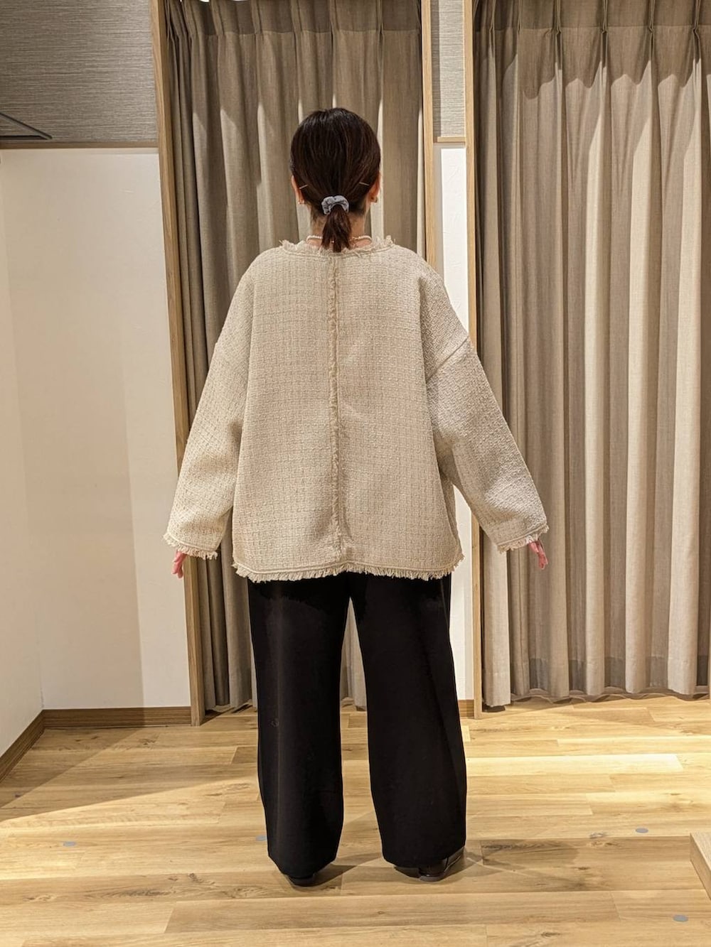 ブラック系のスラックス、ブラック系のショルダーバッグ、ベージュ系のノーカラージャケットを着用したレディースの冬コーディネートの3枚目の写真