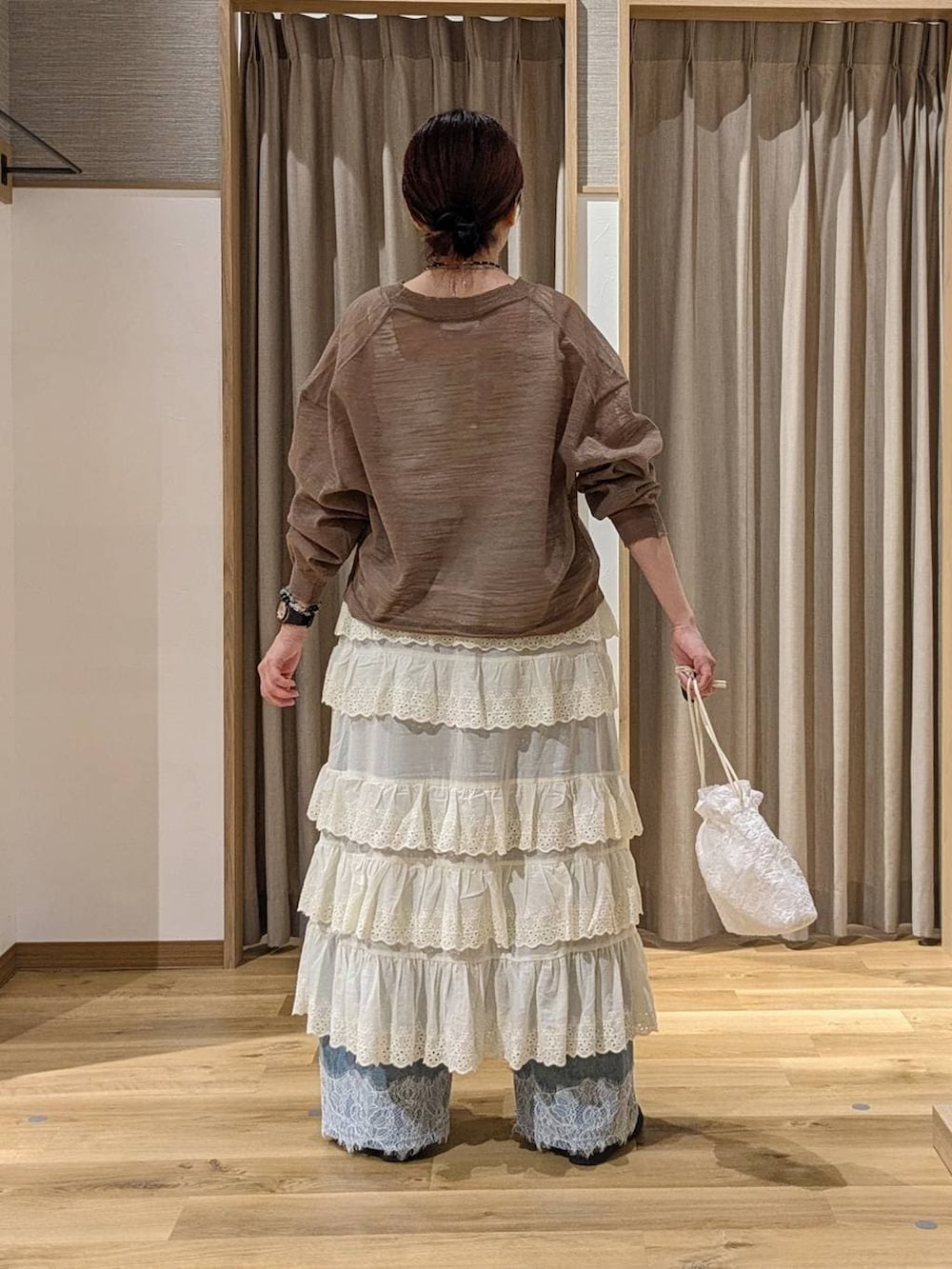 ブルー系のデニムパンツ、ホワイト系のスカート、ホワイト系のタンクトップを着用したレディースの夏コーディネートの3枚目の写真
