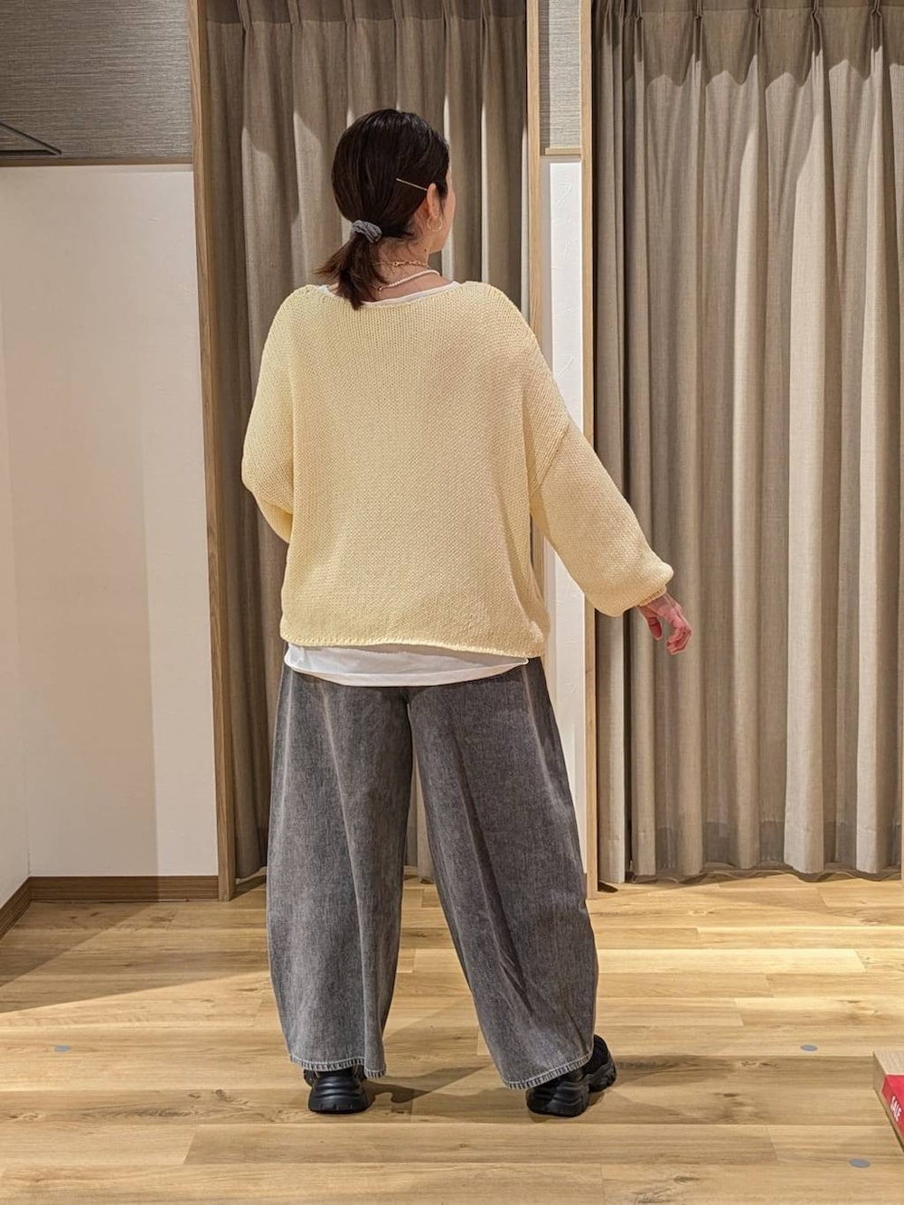 グレー系のデニムパンツ、ブラック系のショルダーバッグ、ブラック系のスニーカーを着用したレディースの春コーディネートの2枚目の写真