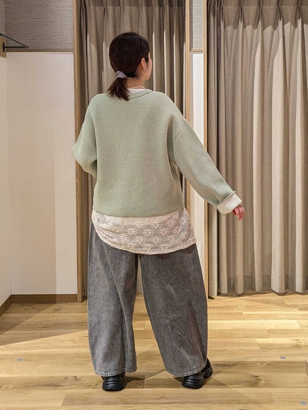 グレー系のデニムパンツ、ブラック系のスニーカー、ホワイト系のベストを着用したレディースの冬コーディネートの2枚目の写真