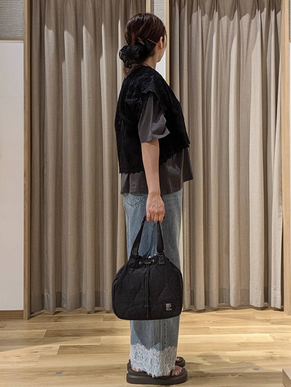 ブルー系のデニムパンツ、ブラック系のベスト、ブラウン系のサンダルを着用したレディースの夏コーディネートの2枚目の写真