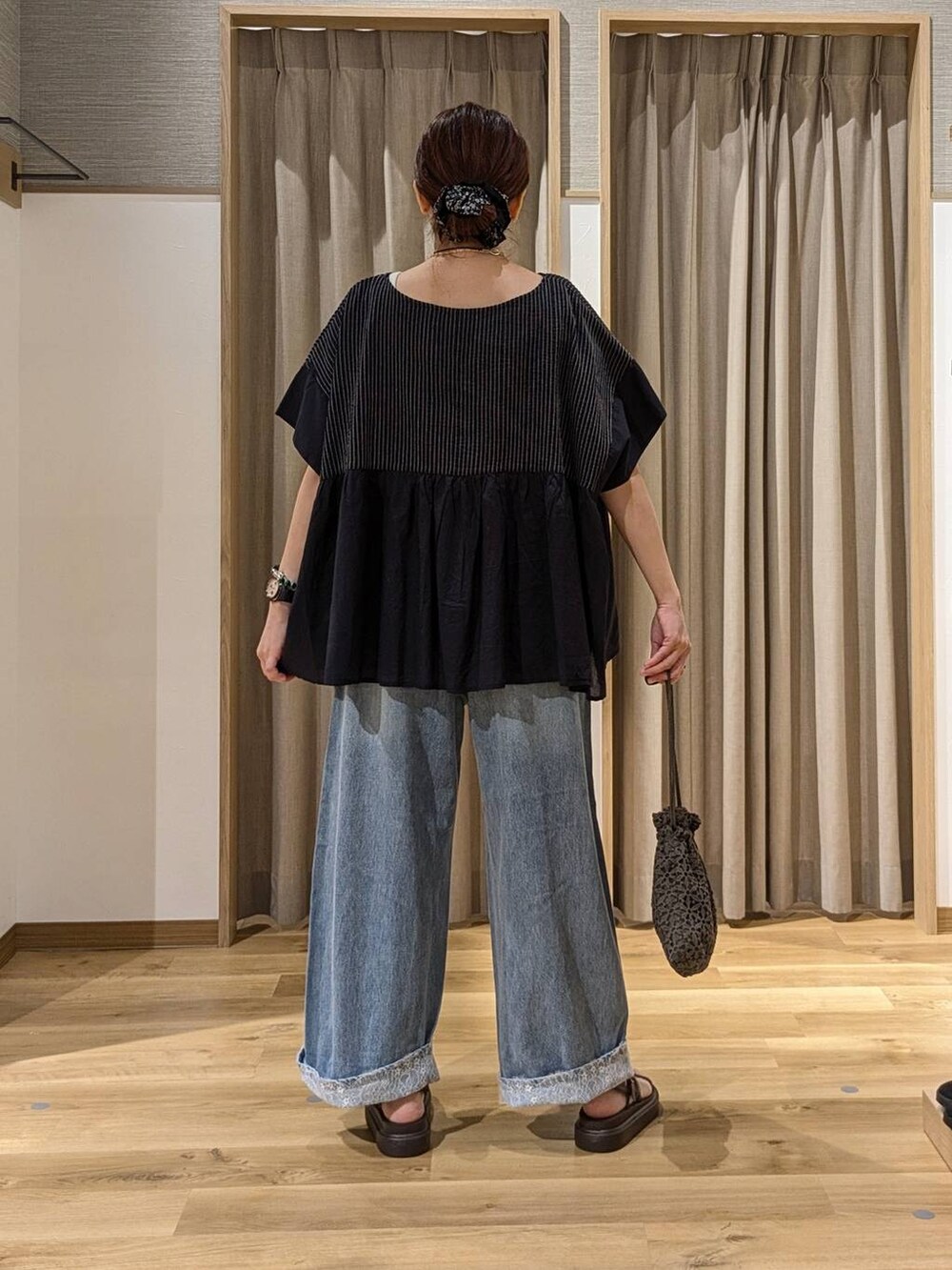 ブルー系のデニムパンツ、ブラウン系のサンダル、ブラック系のシャツ/ブラウスを着用したレディースの夏コーディネートの3枚目の写真