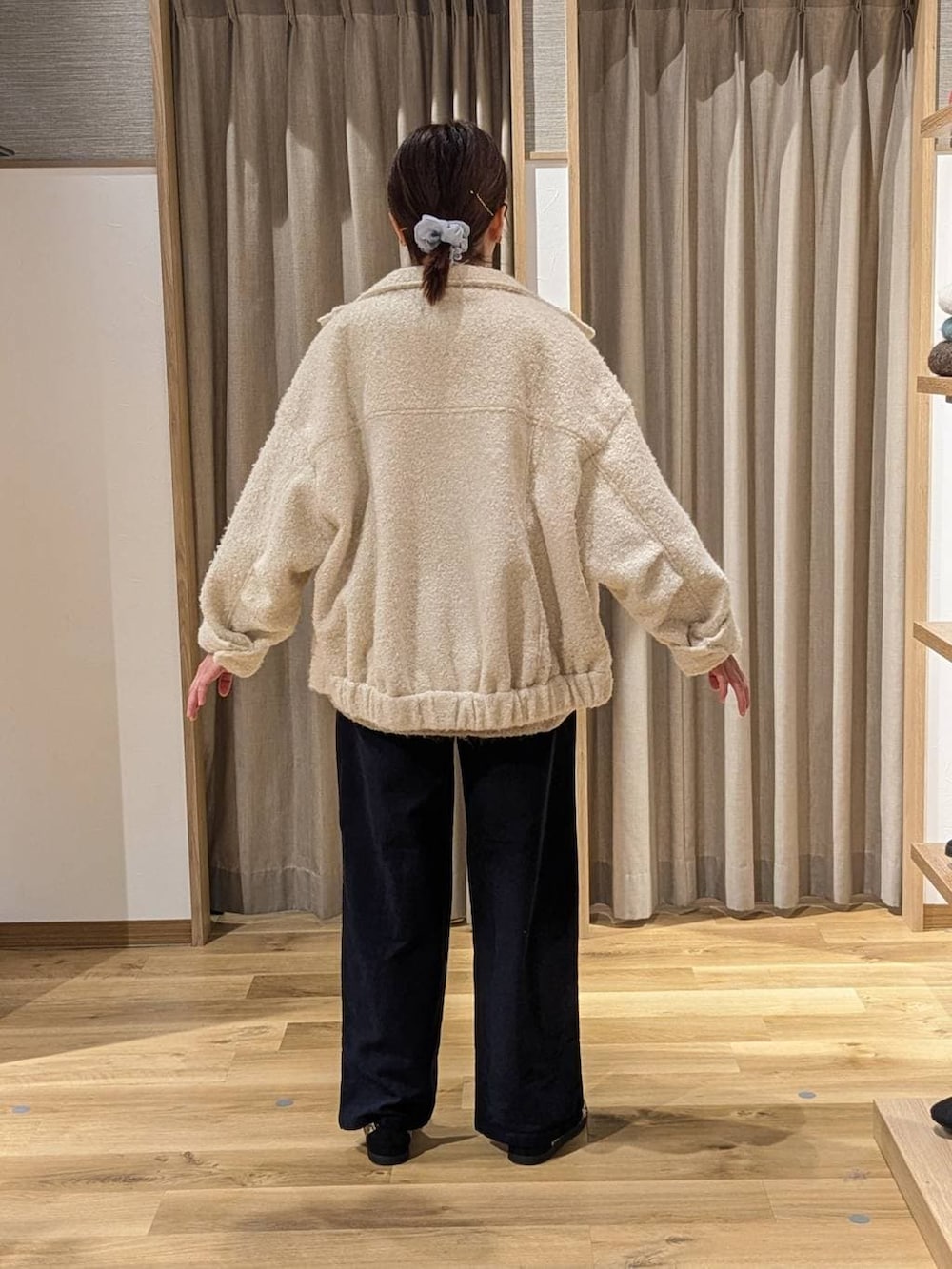 ホワイト系のブルゾン、ベージュ系のニット/セーター、ブラック系のショルダーバッグを着用したレディースの冬コーディネートの2枚目の写真