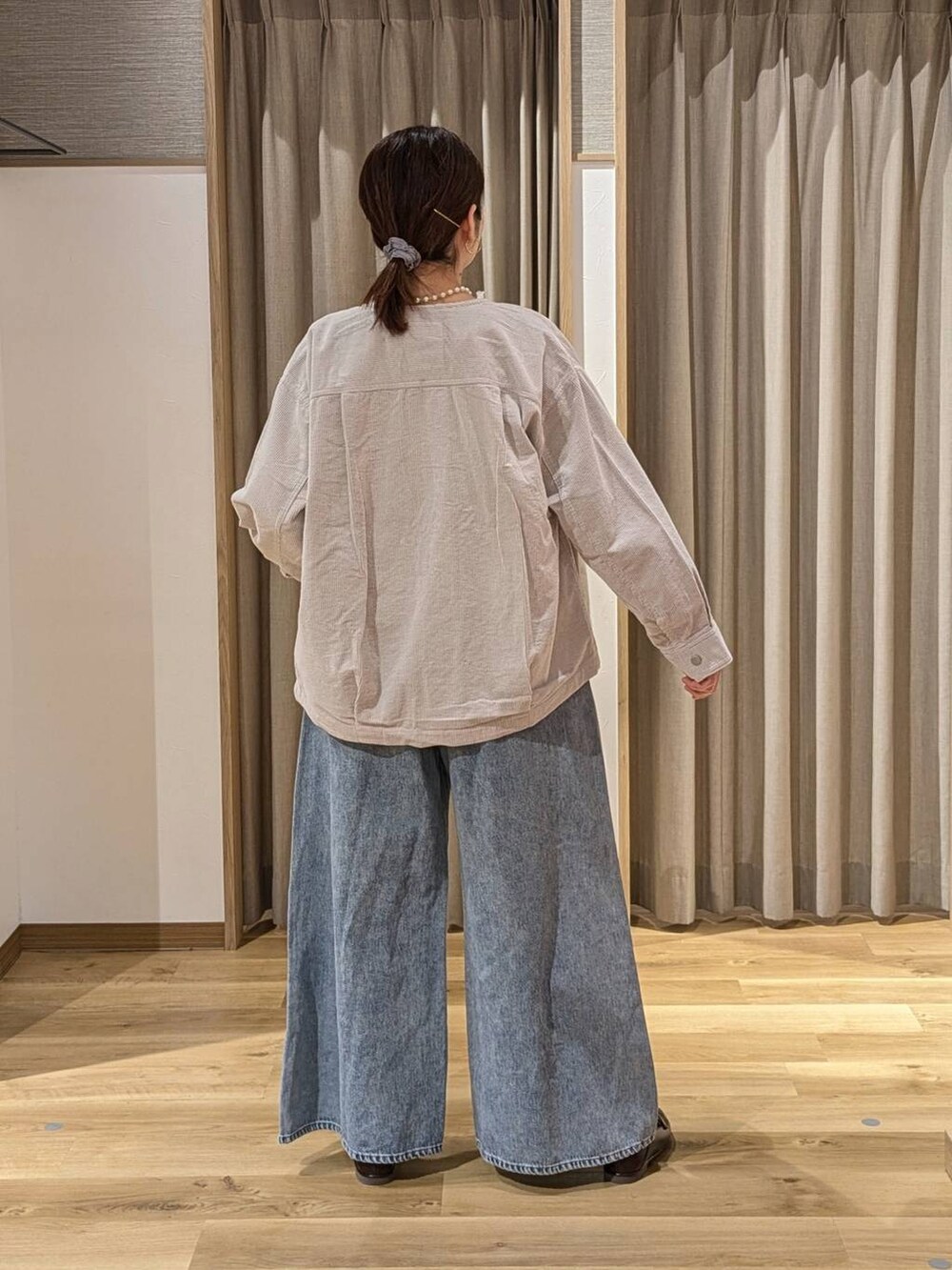 グレー系のノーカラージャケット、ブルー系のデニムパンツ、ブラウン系のショルダーバッグを着用したレディースの冬コーディネートの2枚目の写真