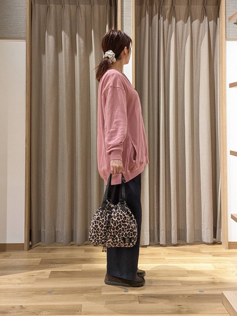 ピンク系のスウェット、ブラウン系のモカシン/デッキシューズ、ブラウン系のショルダーバッグを着用したレディースの秋コーディネートの2枚目の写真