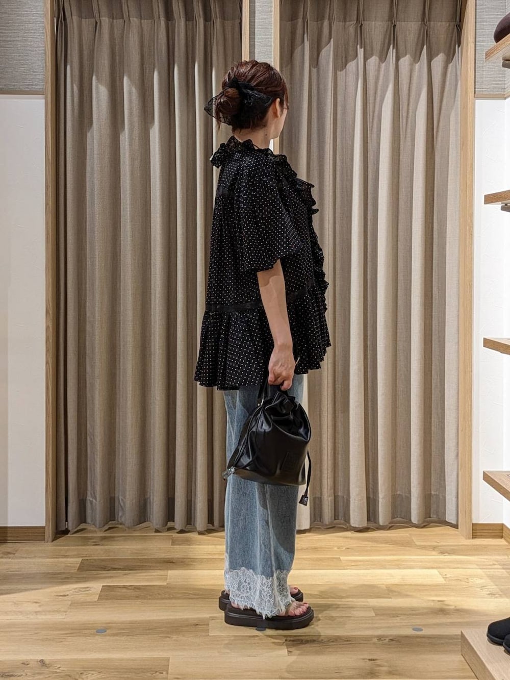 ブルー系のデニムパンツ、ベージュ系のサンダル、ブラック系のトートバッグを着用したレディースの夏コーディネートの3枚目の写真