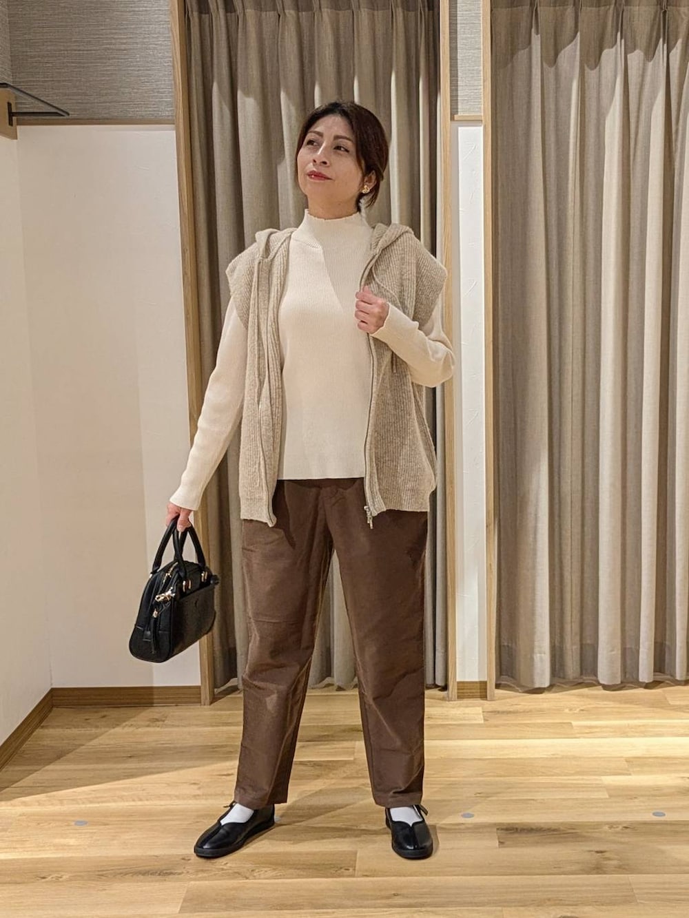 ブラウン系のその他パンツ、ベージュ系のニット/セーター、ブラック系のショルダーバッグを着用したレディースの冬コーディネートの2枚目の写真