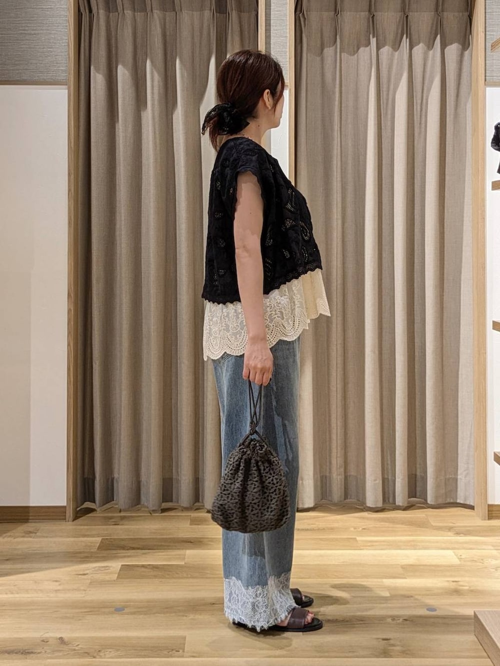ブルー系のデニムパンツ、ブラック系のベスト、ベージュ系のベストを着用したレディースの夏コーディネートの2枚目の写真