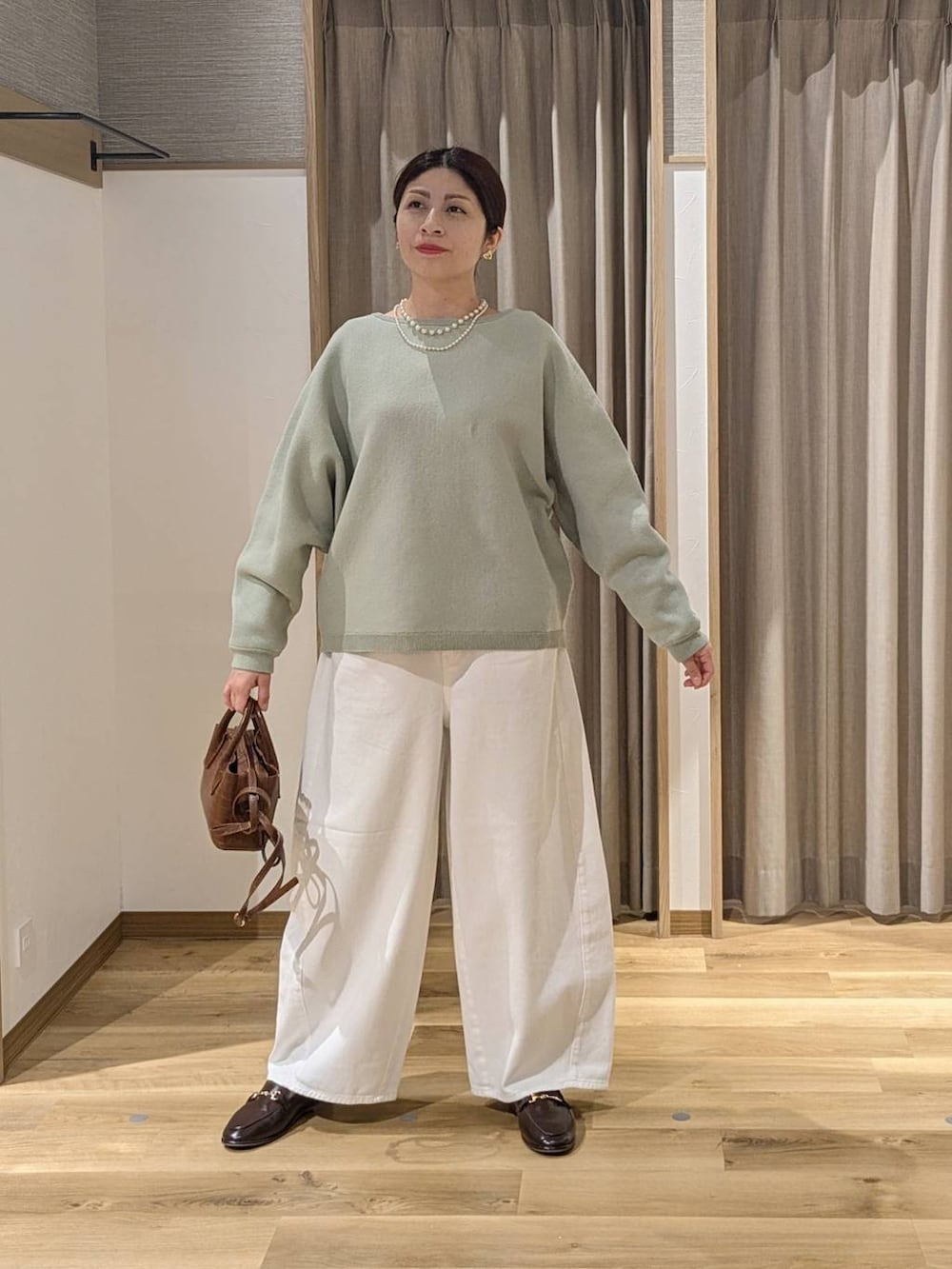 ホワイト系のデニムパンツ、ブラウン系のトートバッグ、ブラウン系のローファーを着用したレディースの春コーディネートの2枚目の写真