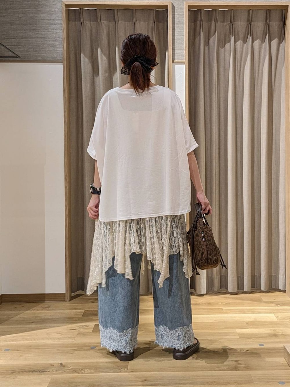 ブルー系のデニムパンツ、ブラウン系のショルダーバッグ、ブラウン系のサンダルを着用したレディースの夏コーディネートの3枚目の写真