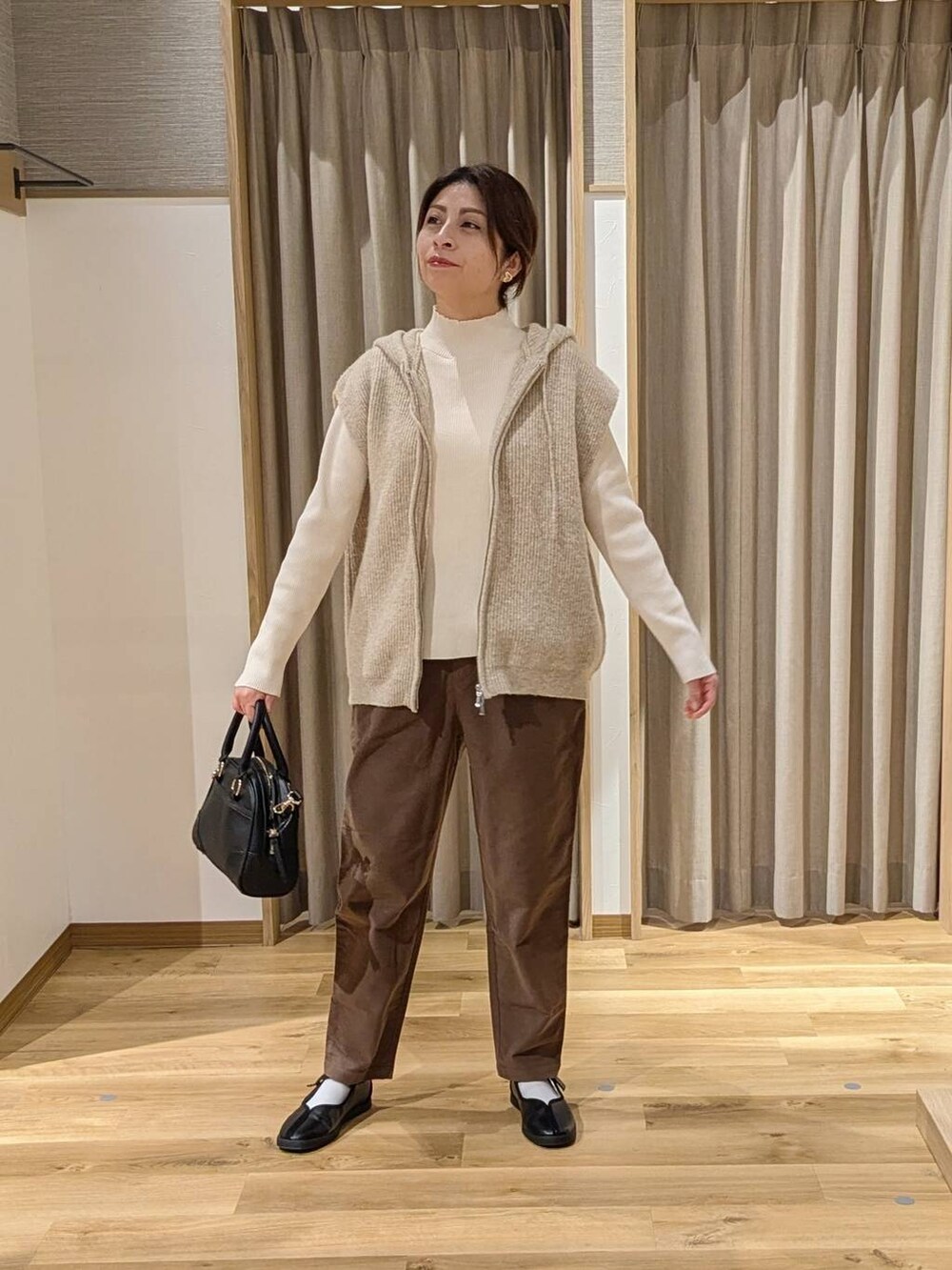 ブラウン系のその他パンツ、ベージュ系のニット/セーター、ブラック系のショルダーバッグを着用したレディースの冬コーディネートの3枚目の写真