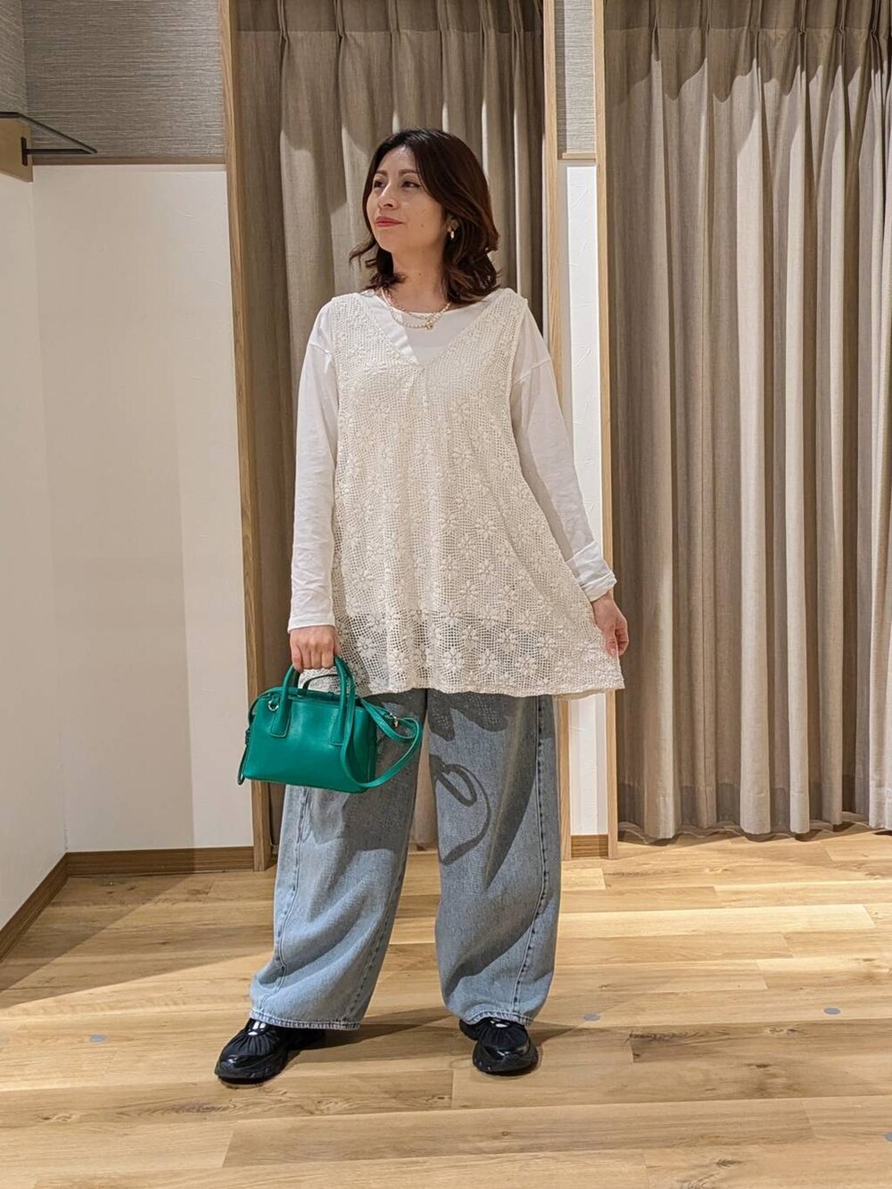 ブルー系のデニムパンツ、ブラック系のスニーカー、グリーン系のトートバッグを着用したレディースの冬コーディネートの2枚目の写真