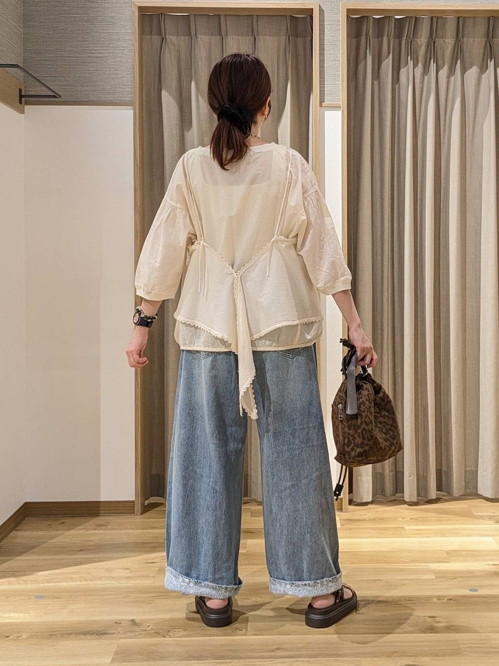 ブルー系のデニムパンツ、ベージュ系のキャミソール、ホワイト系のシャツ/ブラウスを着用したレディースの夏コーディネートの3枚目の写真