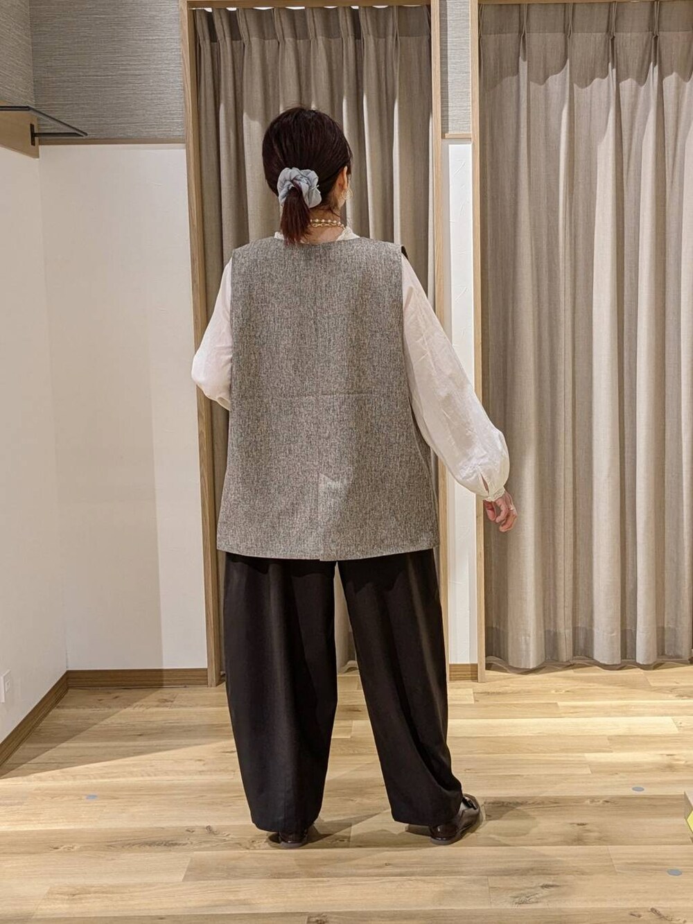 ベージュ系のベスト、グレー系のその他パンツ、ブラウン系のトートバッグを着用したレディースの冬コーディネートの2枚目の写真