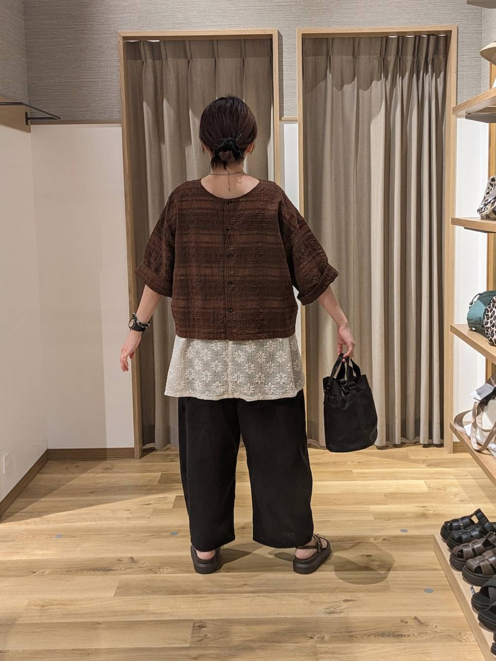 ブラウン系のサンダル、ホワイト系のベスト、ブラック系のその他パンツを着用したレディースの夏コーディネートの2枚目の写真