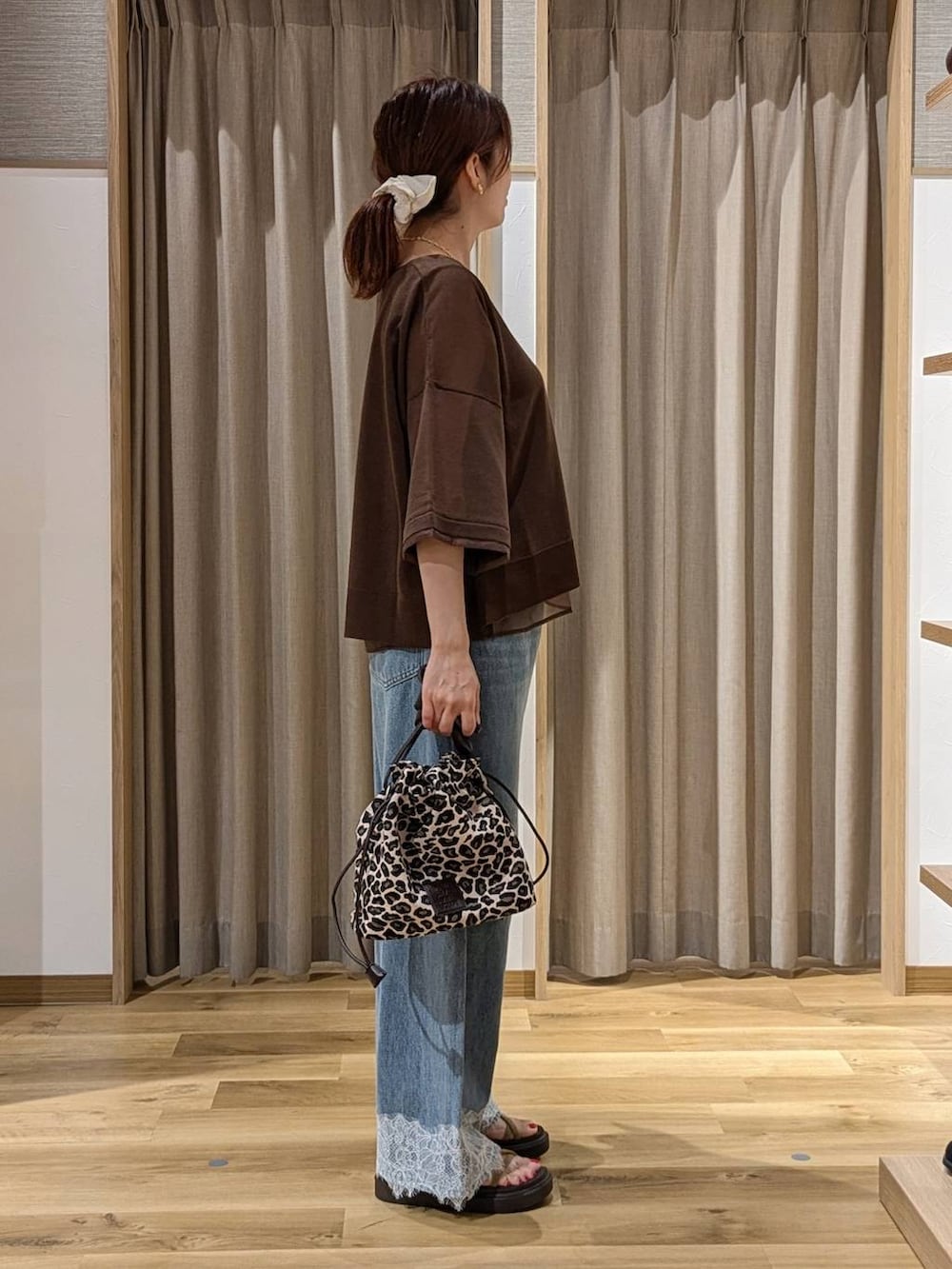 ブルー系のデニムパンツ、ベージュ系のサンダル、ブラウン系のニット/セーターを着用したレディースの夏コーディネートの2枚目の写真