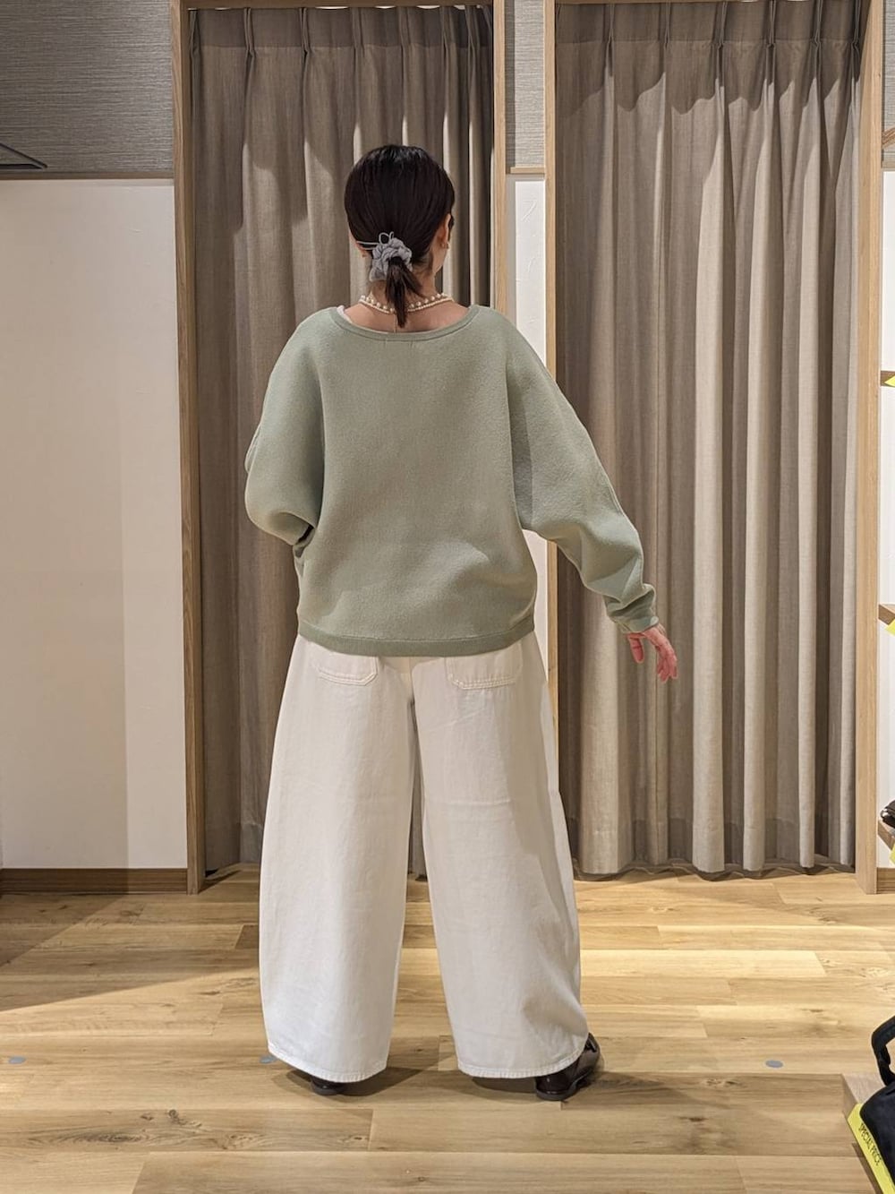 ホワイト系のデニムパンツ、ブラウン系のトートバッグ、ブラウン系のローファーを着用したレディースの春コーディネートの3枚目の写真