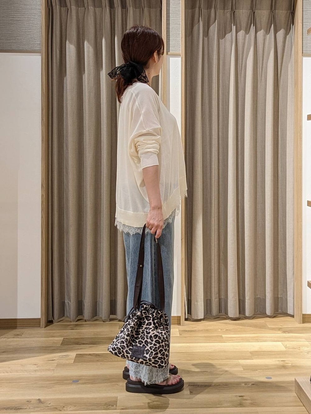 ブルー系のデニムパンツ、ホワイト系のカーディガン/ボレロ、ベージュ系のサンダルを着用したレディースの夏コーディネートの2枚目の写真