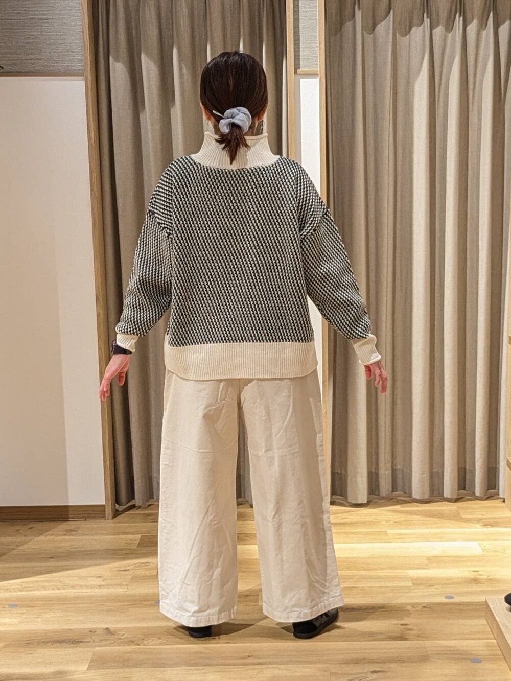 ベージュ系のニット/セーター、ブラウン系のショルダーバッグ、ブラック系のスニーカーを着用したレディースの冬コーディネートの2枚目の写真