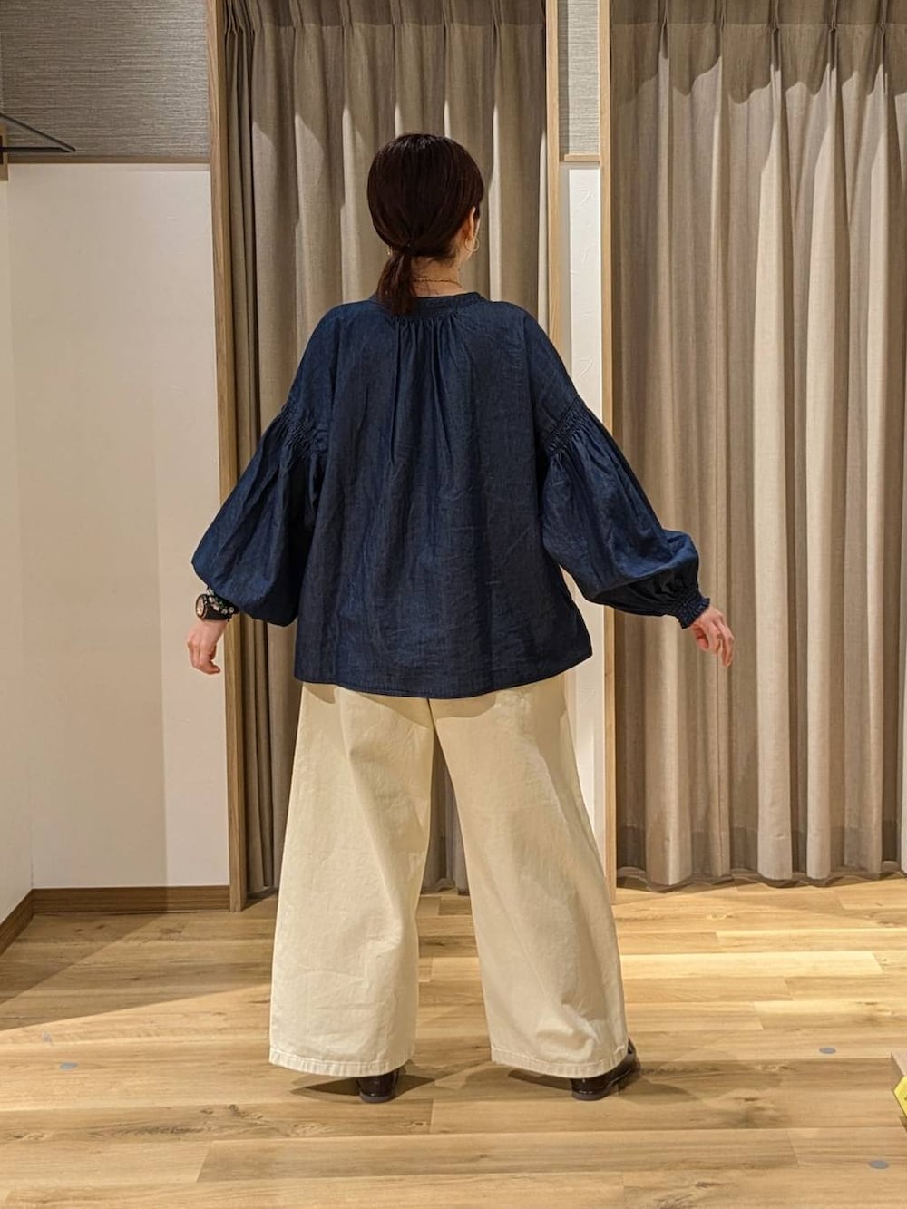 イエロー系のチノパンツ、ブラウン系のトートバッグ、ブラウン系のローファーを着用したレディースの冬コーディネートの2枚目の写真