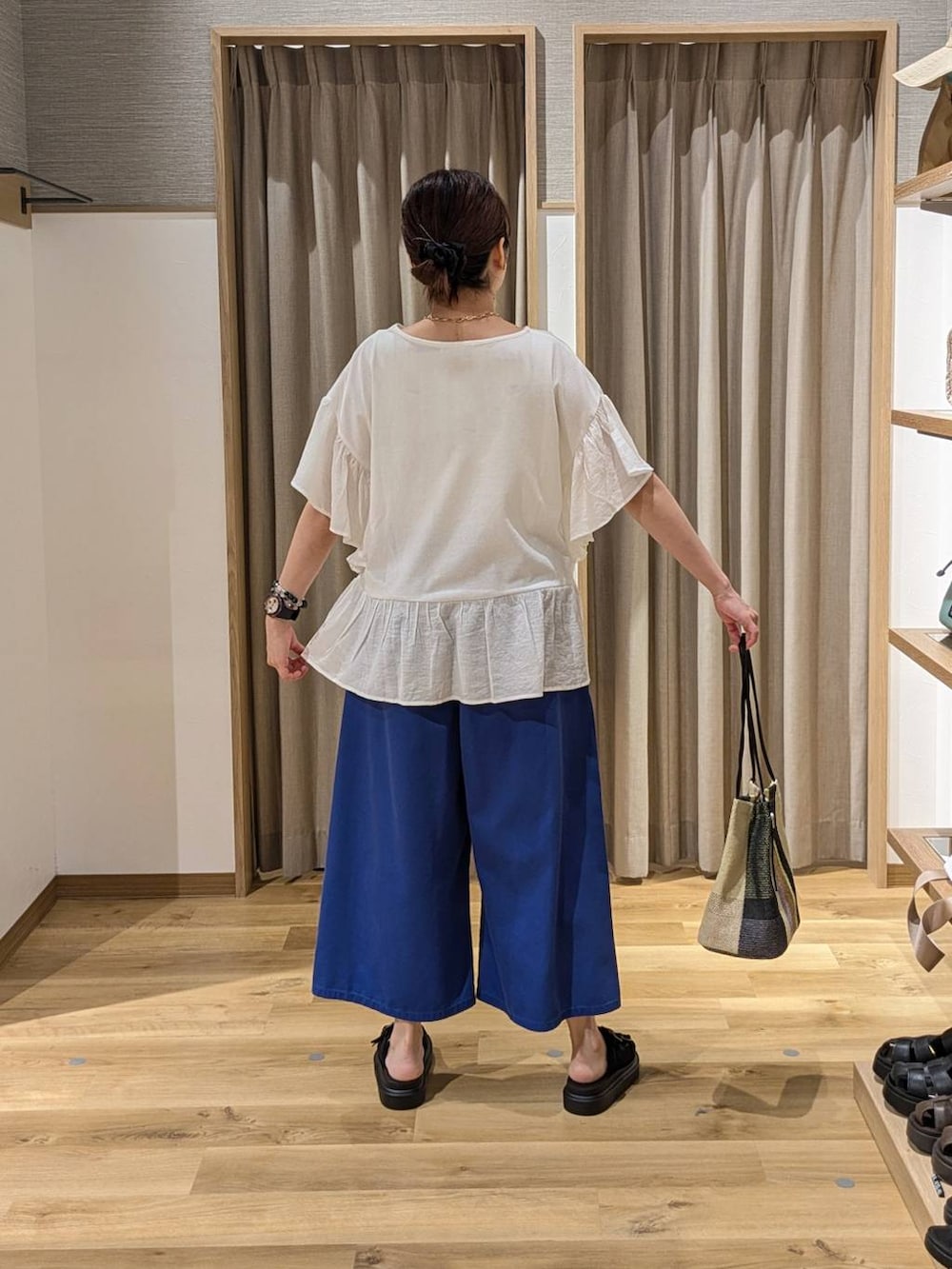 ブラック系のトートバッグ、ブラック系のサンダル、ブルー系のその他パンツを着用したレディースの夏コーディネートの2枚目の写真
