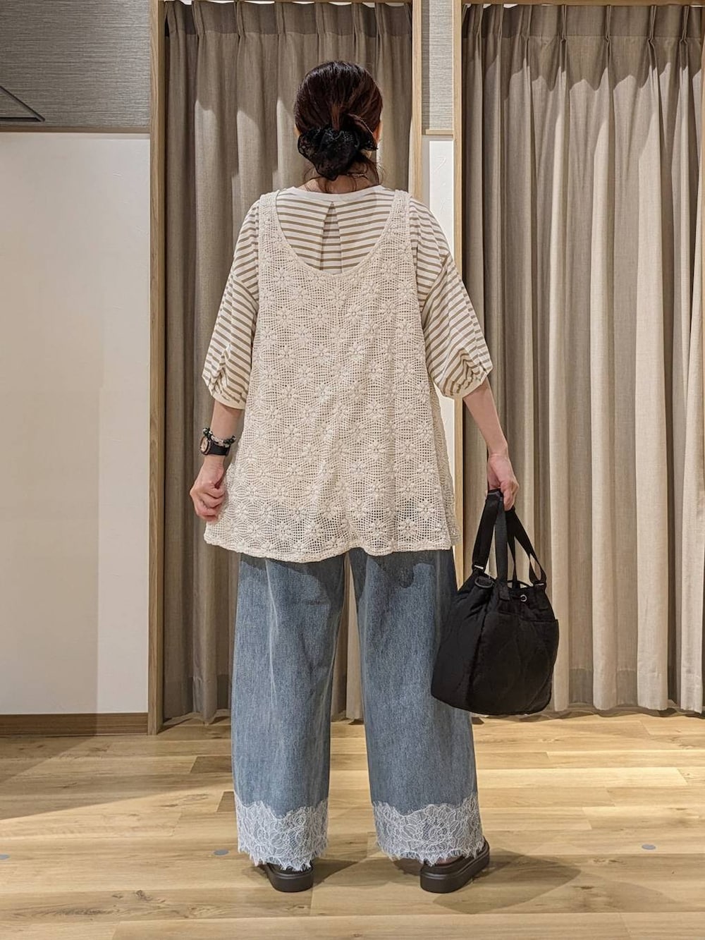 ブルー系のデニムパンツ、ブラウン系のサンダル、ホワイト系のベストを着用したレディースの夏コーディネートの3枚目の写真