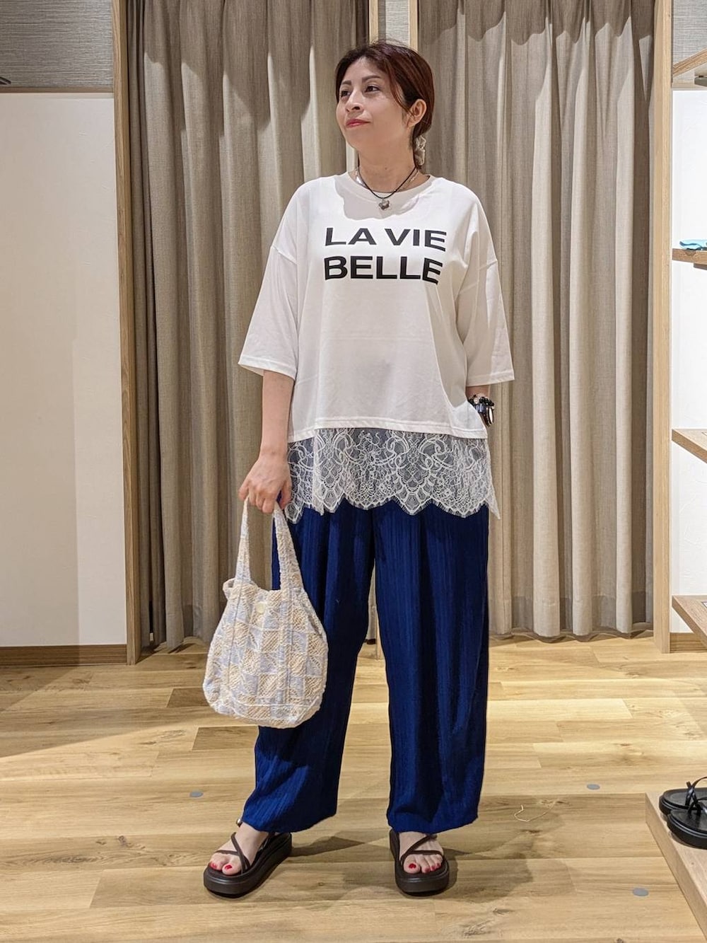ブルー系のその他パンツ、ブラウン系のサンダル、ブルー系のトートバッグを着用したレディースの夏コーディネートの2枚目の写真