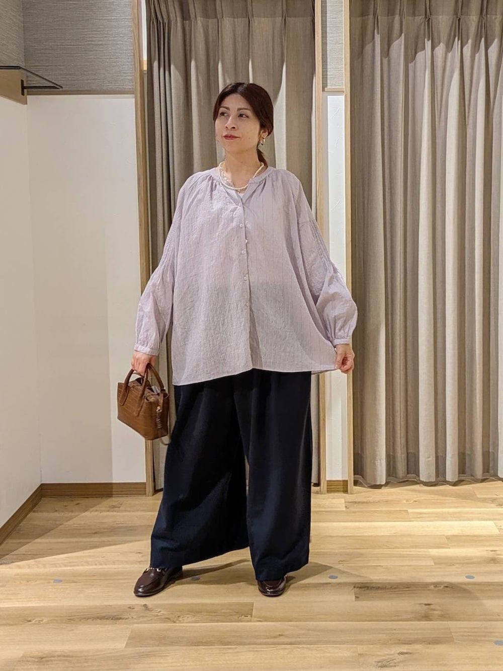 ブラウン系のトートバッグ、ブラウン系のローファー、ブルー系のその他パンツを着用したレディースの冬コーディネートの3枚目の写真