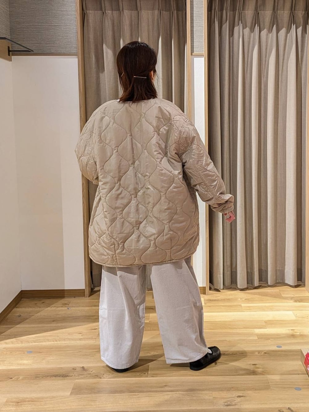 ベージュ系のノーカラーコート、グレー系のその他パンツ、ブラック系のスニーカーを着用したレディースの冬コーディネートの3枚目の写真