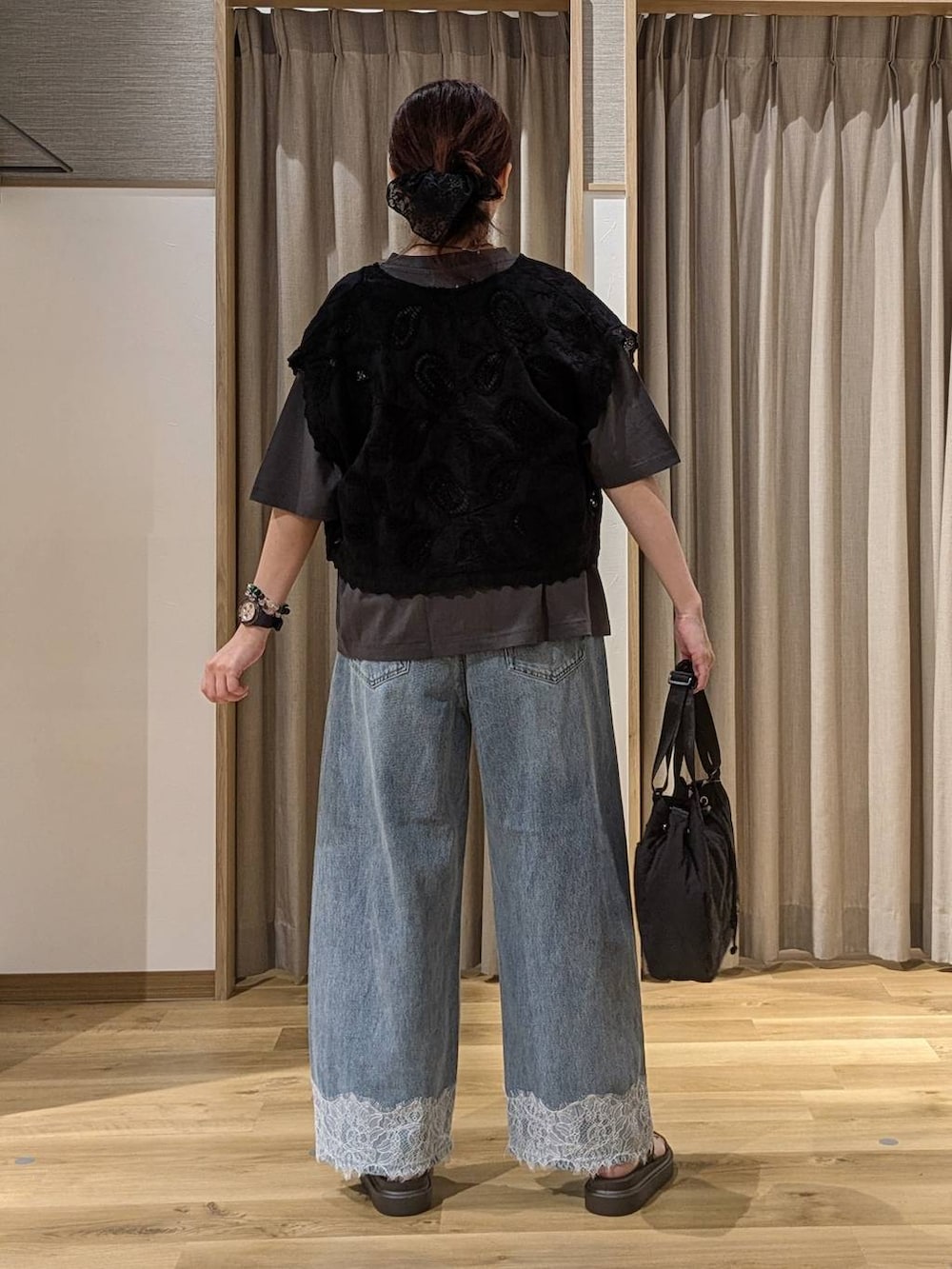 ブルー系のデニムパンツ、ブラック系のベスト、ブラウン系のサンダルを着用したレディースの夏コーディネートの3枚目の写真