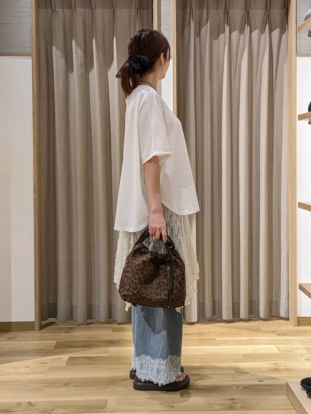 ブルー系のデニムパンツ、ブラウン系のショルダーバッグ、ブラウン系のサンダルを着用したレディースの夏コーディネートの2枚目の写真