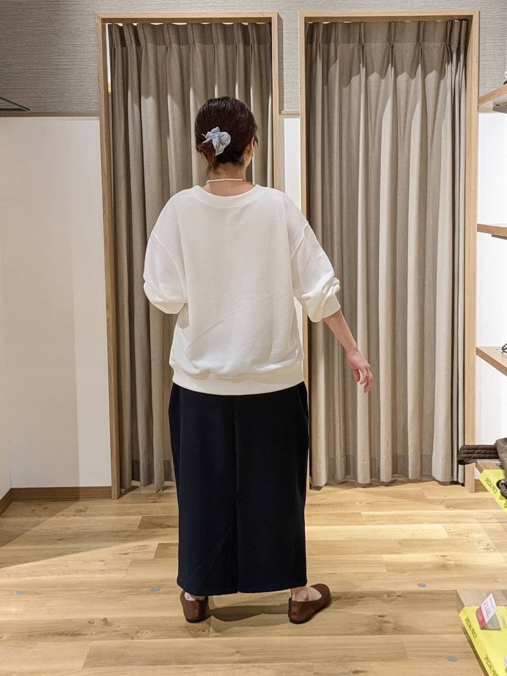 ブルー系のスカート、ホワイト系のスウェット、ブラウン系のパンプスを着用したレディースの春コーディネートの2枚目の写真