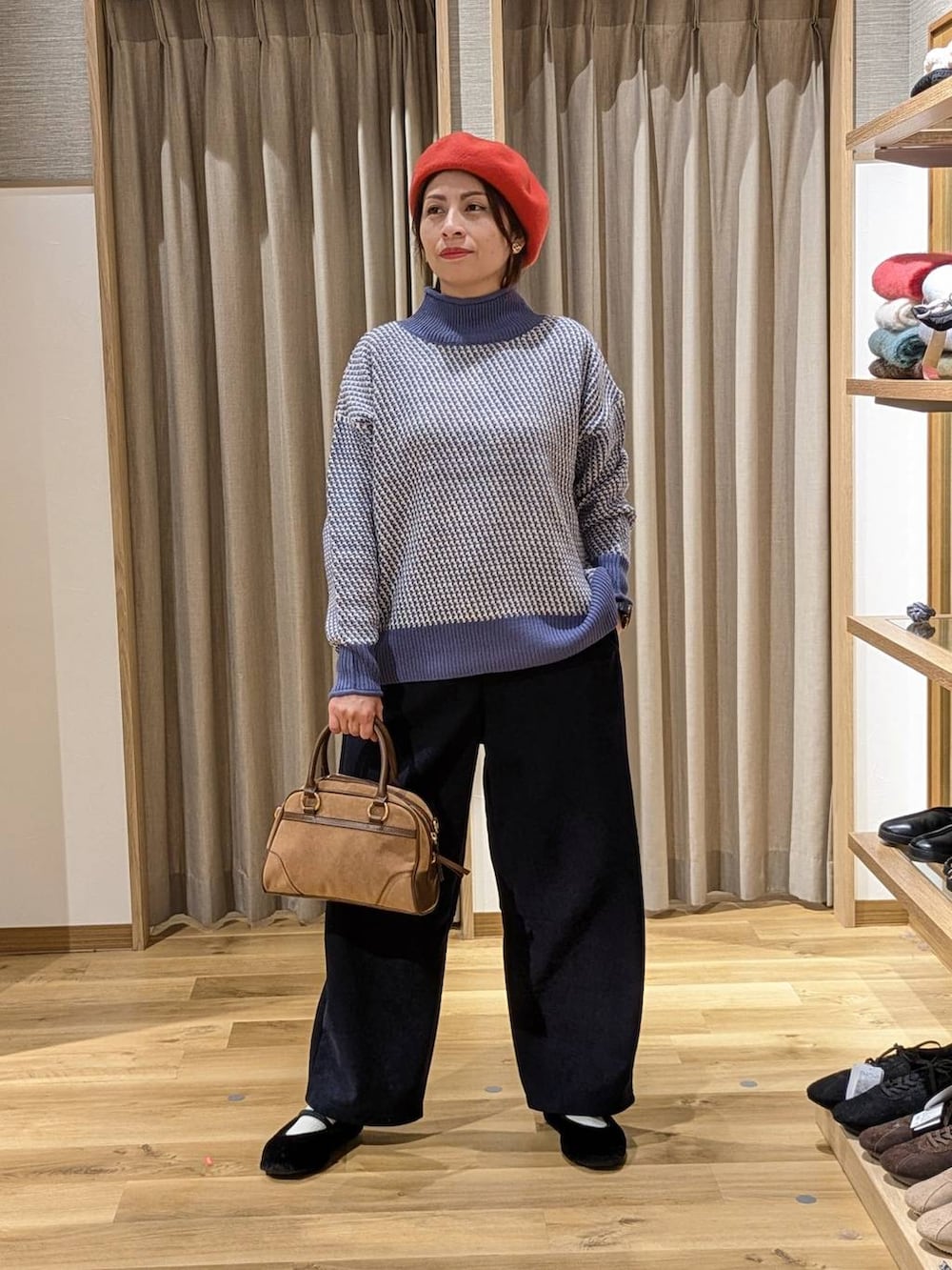 ブルー系のニット/セーター、ブラック系のパンプス、ブラウン系のショルダーバッグを着用したレディースの冬コーディネートの2枚目の写真