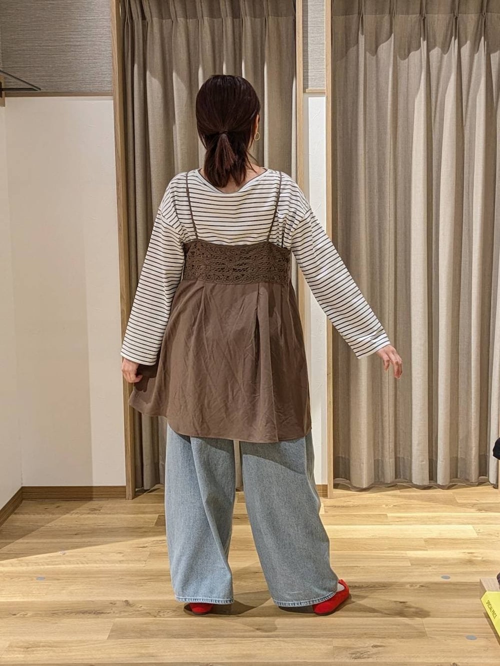 レッド系のパンプス、ブルー系のデニムパンツ、ブラウン系のトートバッグを着用したレディースの冬コーディネートの2枚目の写真