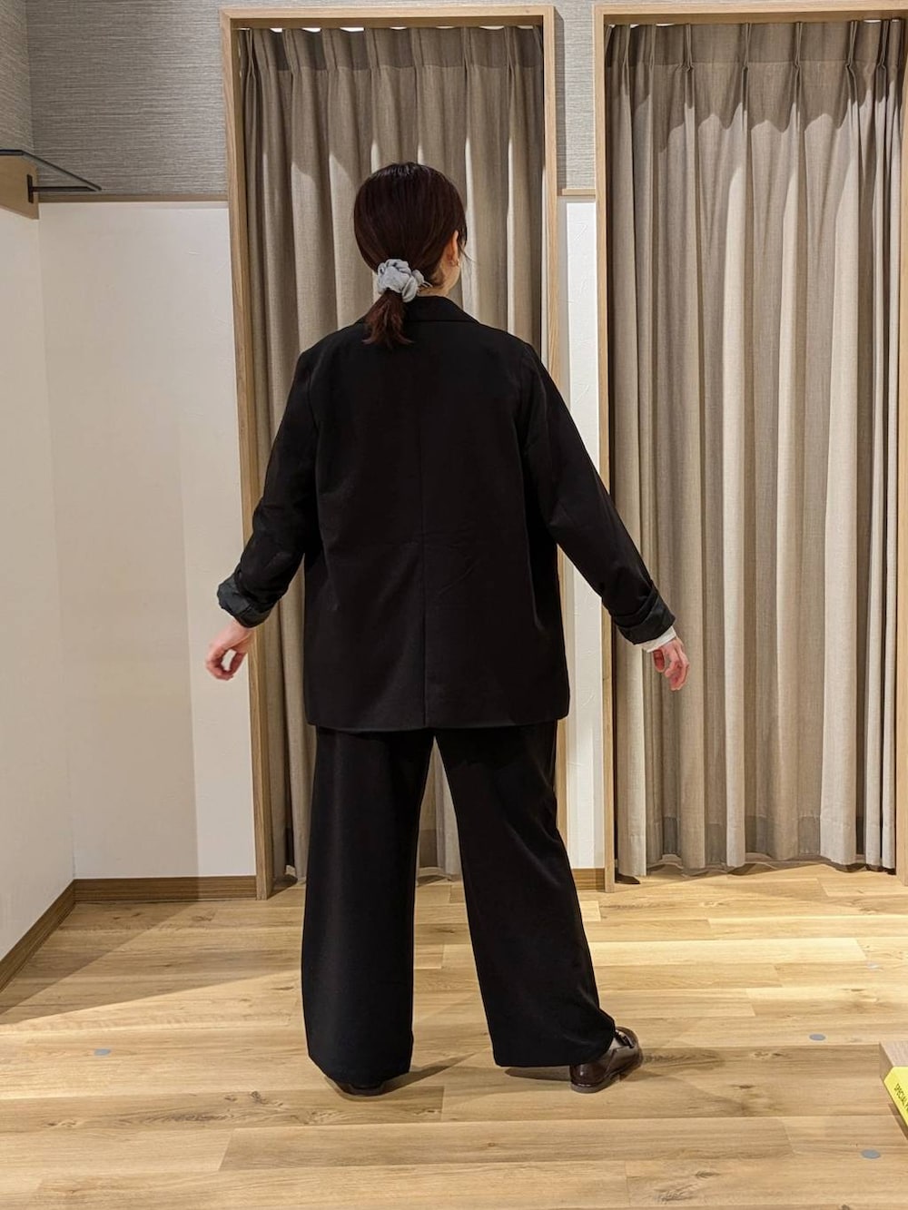 ブラック系のテーラードジャケット、ブラック系のスラックス、ブラウン系のトートバッグを着用したレディースの冬コーディネートの2枚目の写真