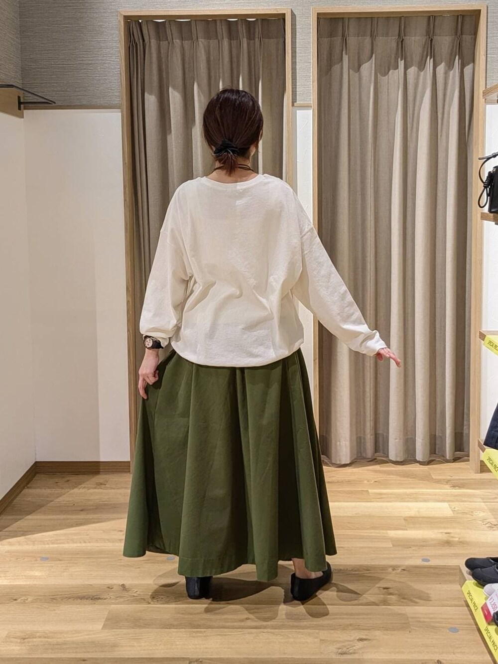 ホワイト系のTシャツ/カットソー、グリーン系のスカート、ベージュ系のトートバッグを着用したレディースの春コーディネートの2枚目の写真