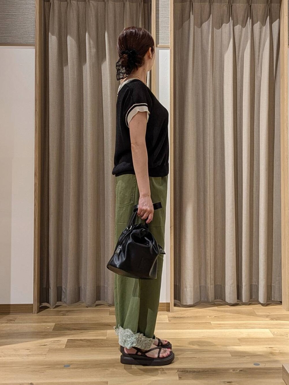 グリーン系のデニムパンツ、ブラック系のニット/セーター、ブラウン系のサンダルを着用したレディースの夏コーディネートの2枚目の写真