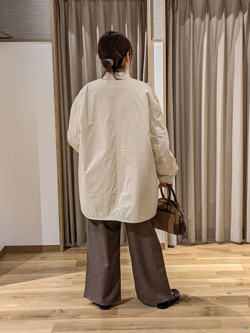 ベージュ系のノーカラーコート、ベージュ系のニット/セーター、ブラウン系のその他パンツを着用したレディースの冬コーディネートの2枚目の写真