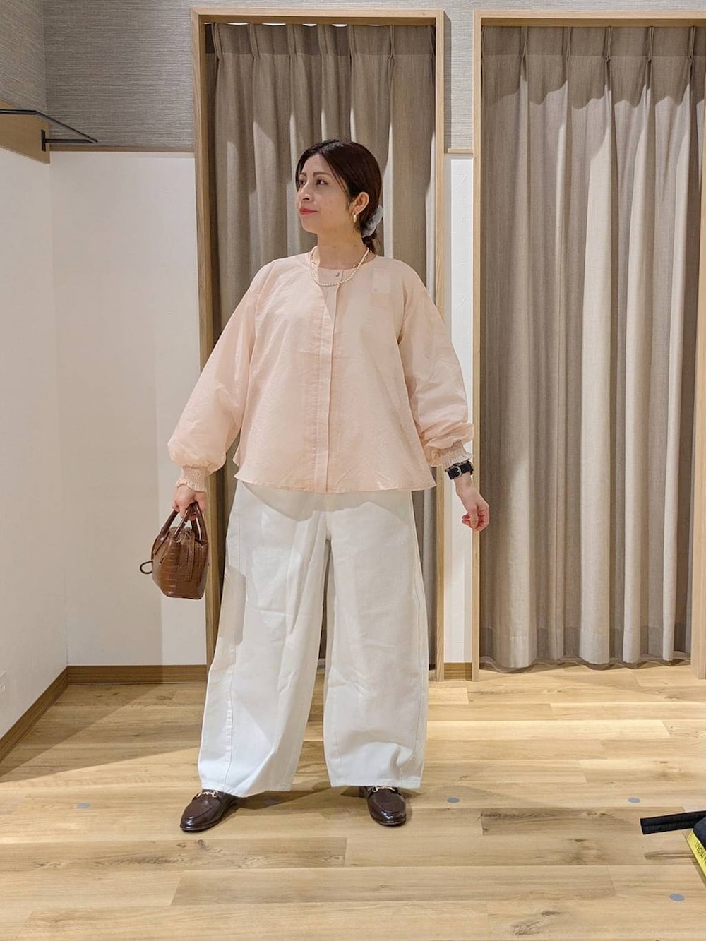 ホワイト系のデニムパンツ、ブラウン系のトートバッグ、ブラウン系のローファーを着用したレディースの春コーディネートの2枚目の写真