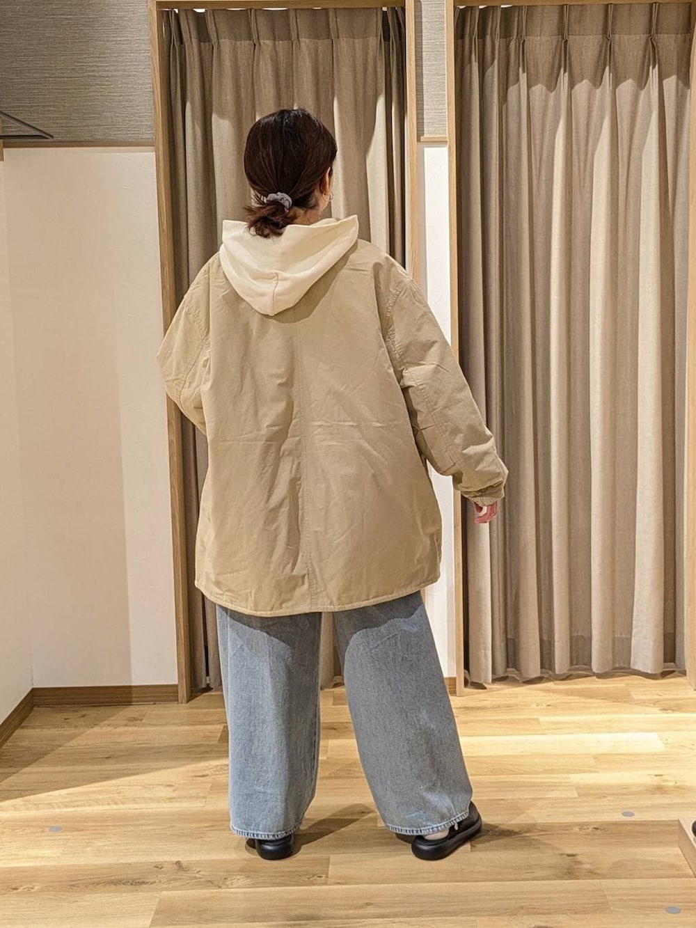 ベージュ系のノーカラーコート、ブラック系のサンダル、ホワイト系のパーカーを着用したレディースの冬コーディネートの2枚目の写真