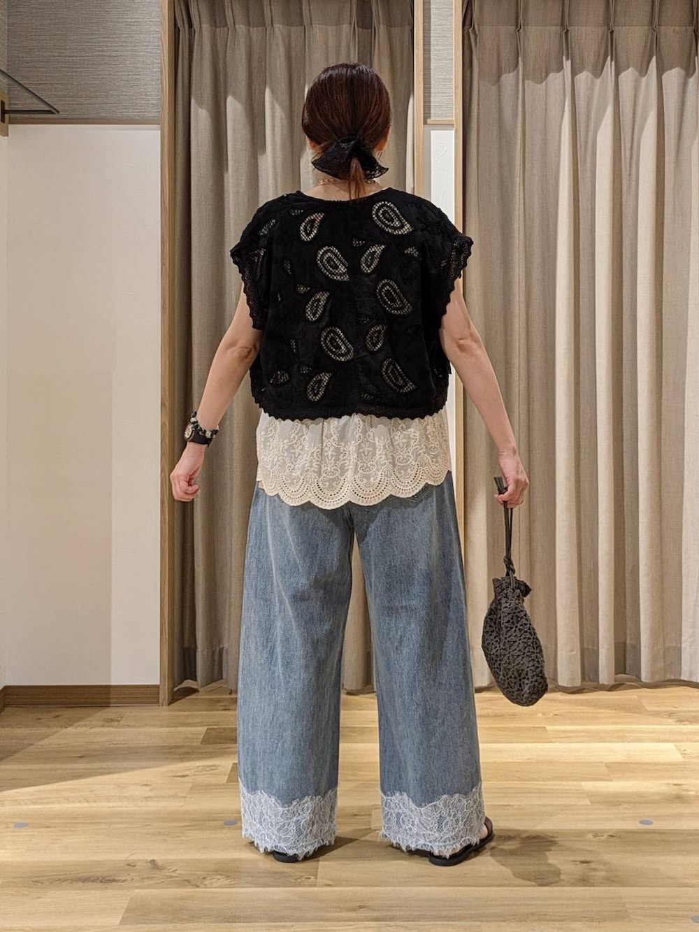 ブルー系のデニムパンツ、ブラック系のベスト、ベージュ系のベストを着用したレディースの夏コーディネートの3枚目の写真